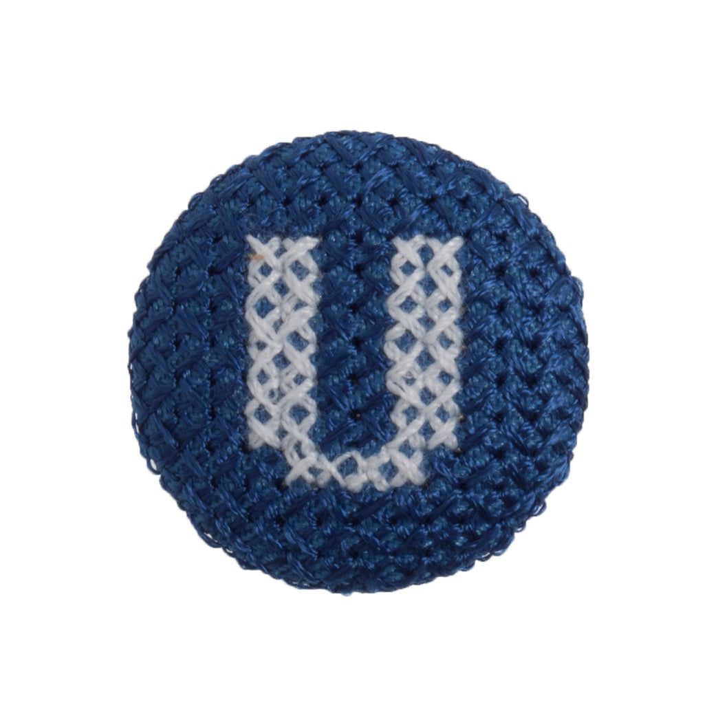 Round navy blue fabric button with a white cross stitch letter U