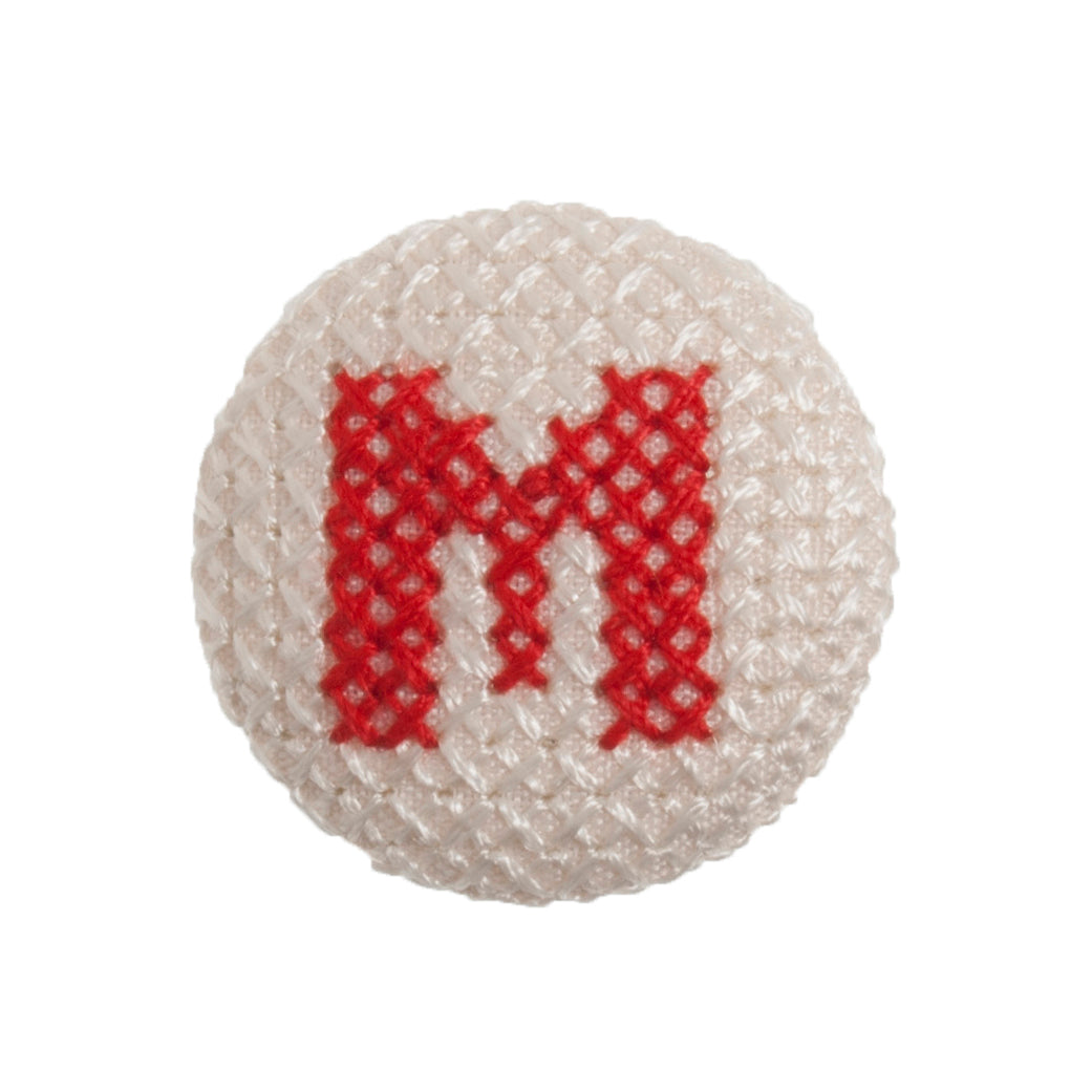Round button with a red cross-stitch letter M