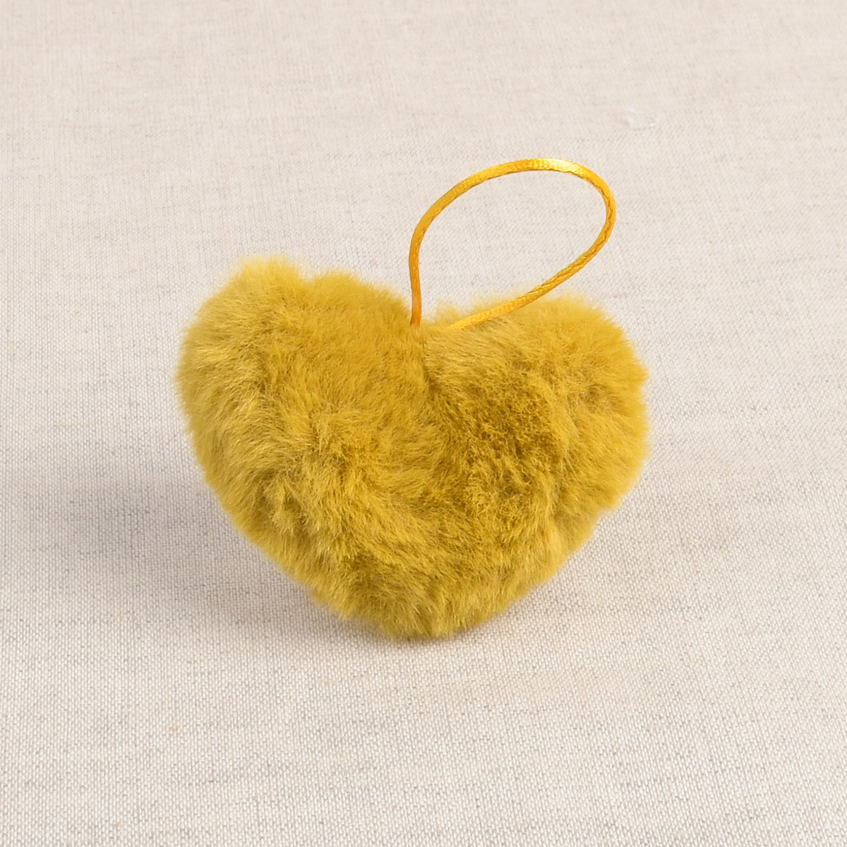 Mustard faux fur heart-shaped pom pom with a hanging loop