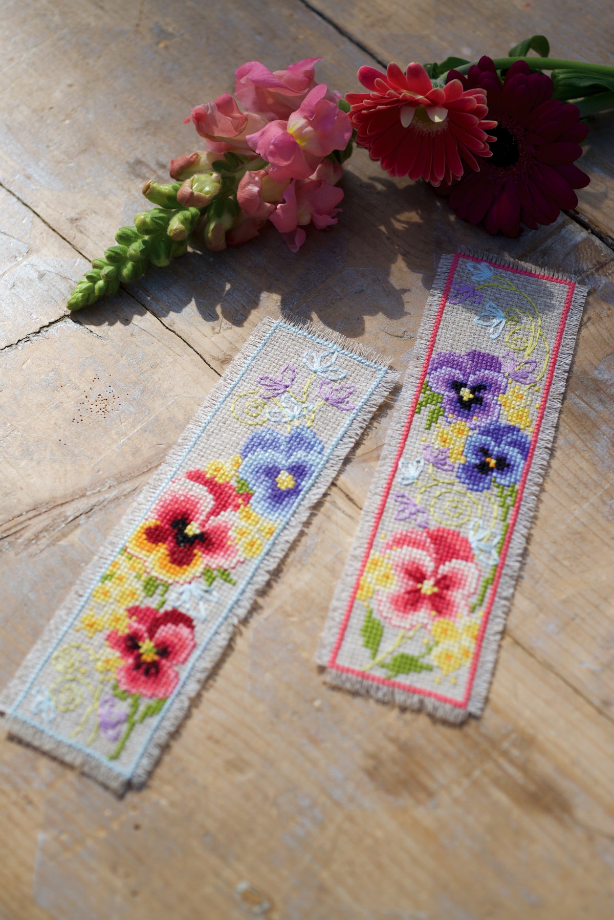 Two cross stitched bookmarks with purple violets