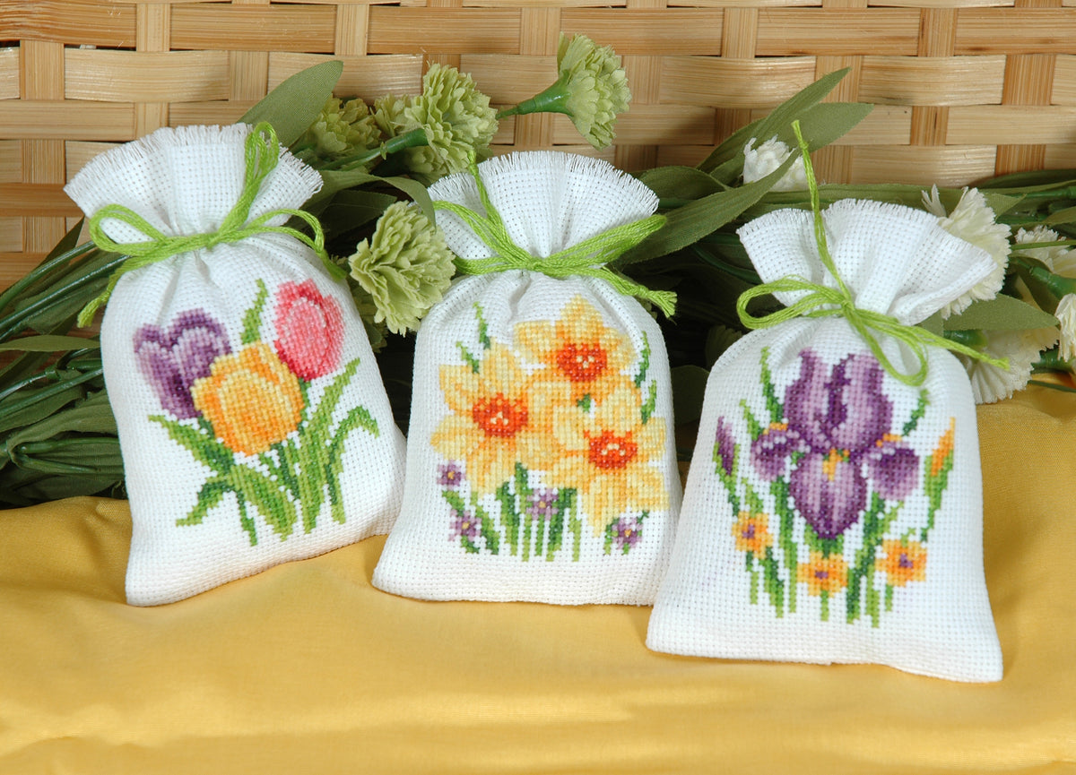 Three small white gift bags cross stitched with flowers