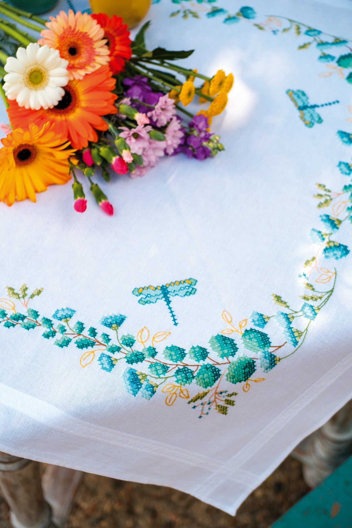 Square white tablecloth embroidered with green eucalyptus sprigs