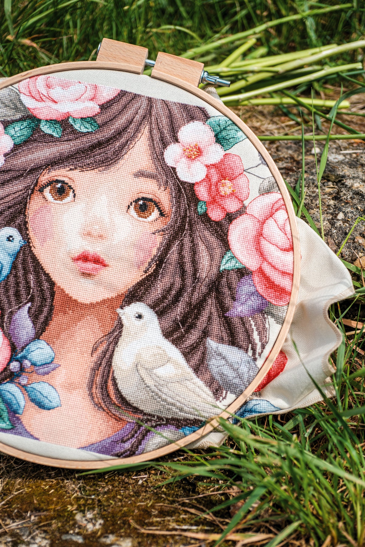 Cross stitch picture of a woman surrounded by roses