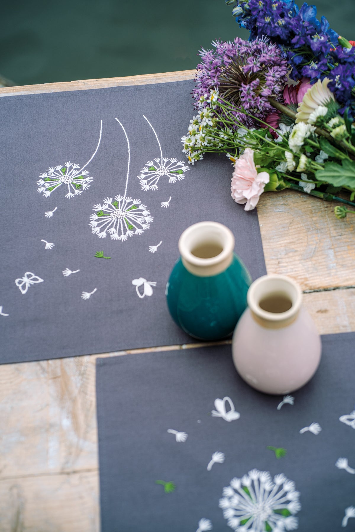Two dark grey placemats embroidered with fluffy flowers