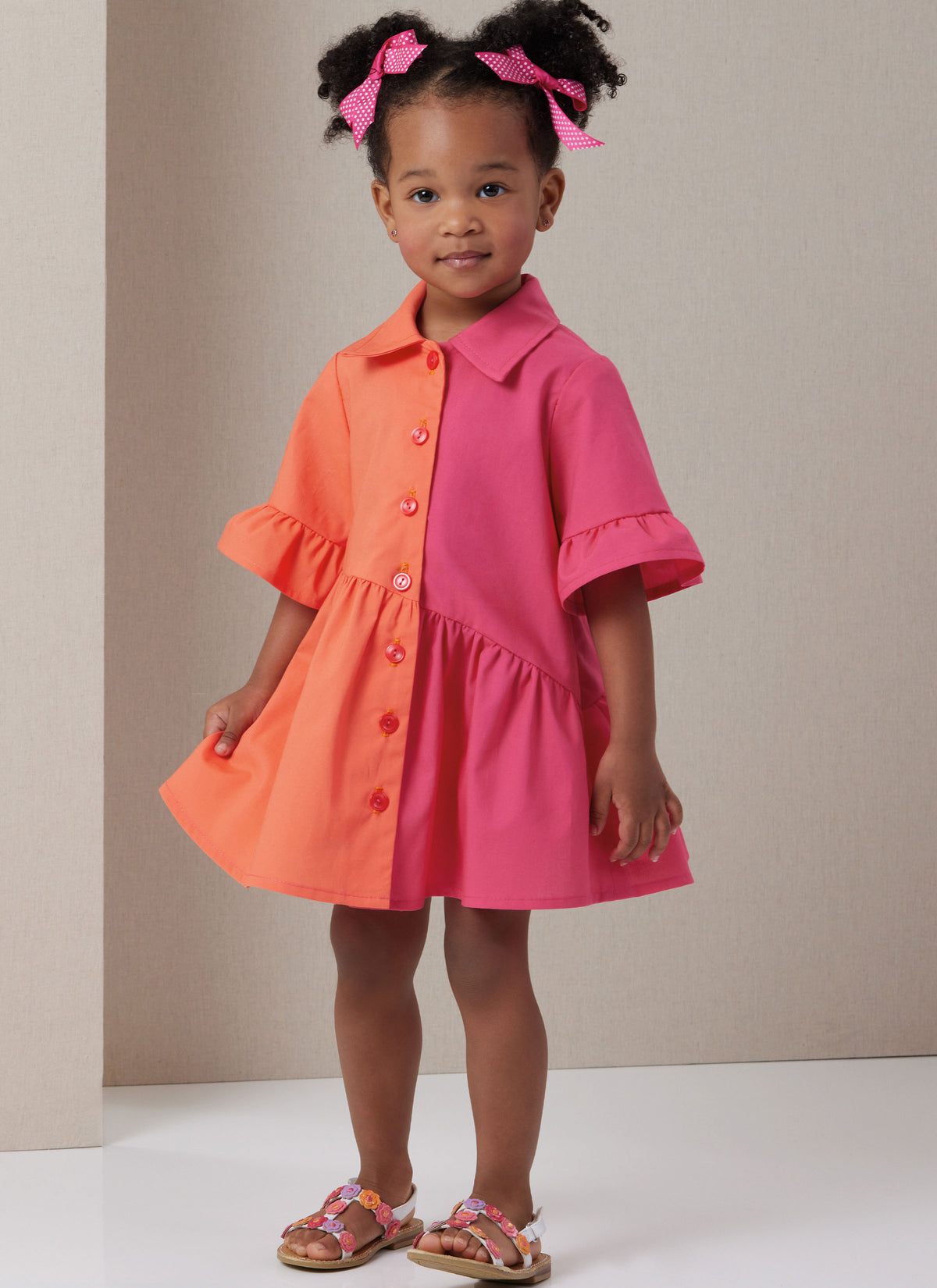 Butterick B7049 sewing pattern envelope showing toddler button-front dress designs
