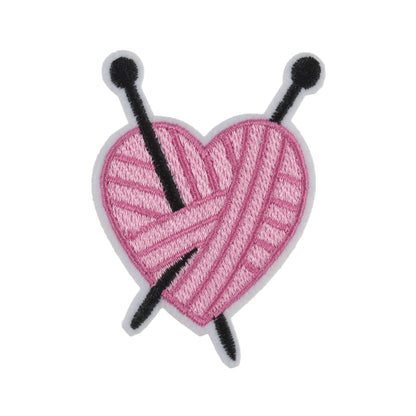 Pink yarn heart motif with black knitting needles