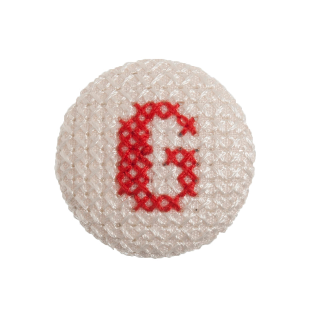 Round button with a red cross-stitch letter G