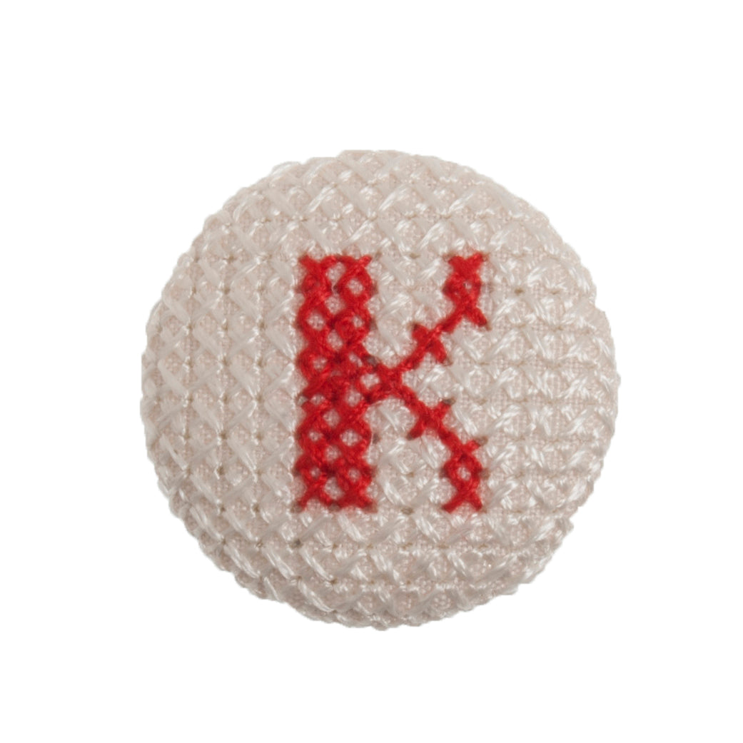 Round button with a red cross-stitch letter K