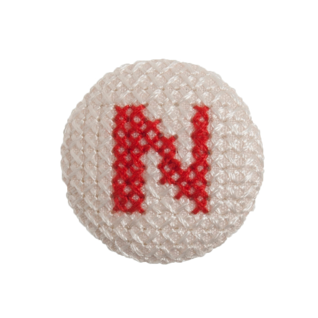 Round button with a red cross-stitch letter N