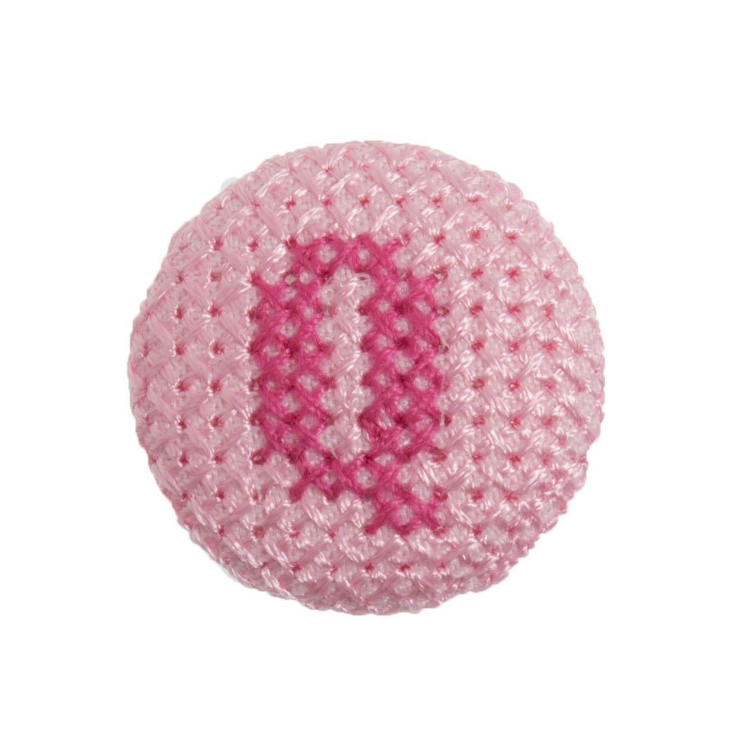 Round light pink fabric button with a dark pink cross stitch letter Q