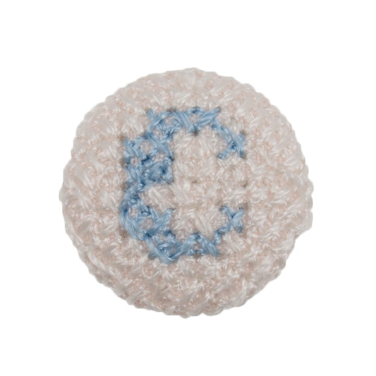 Round white fabric button with a light blue cross stitch letter C