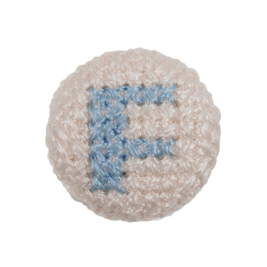 Round white fabric button with a light blue cross stitch letter F