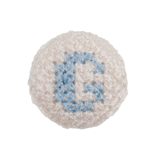 Round white fabric button with a light blue cross stitch letter G