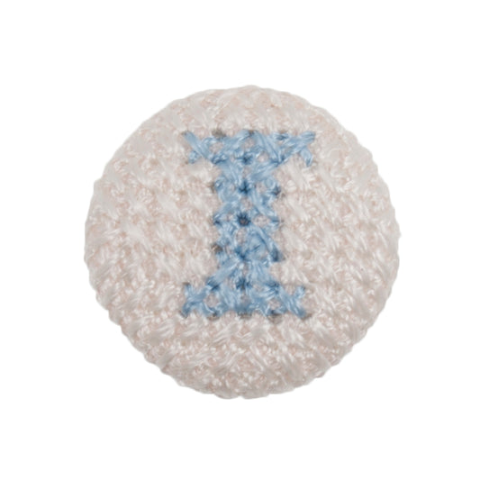 Round white fabric button with a light blue cross stitch letter I