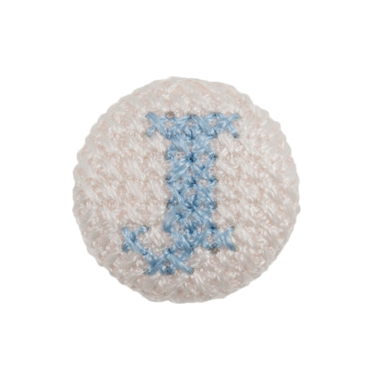 Round white fabric button with a light blue cross stitch letter J
