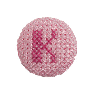 Pink fabric-covered button with a darker pink cross-stitched letter K