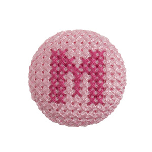 Pink fabric-covered button with a darker pink cross-stitched letter M