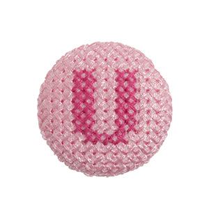 Pink fabric-covered button with a darker pink cross-stitched letter U
