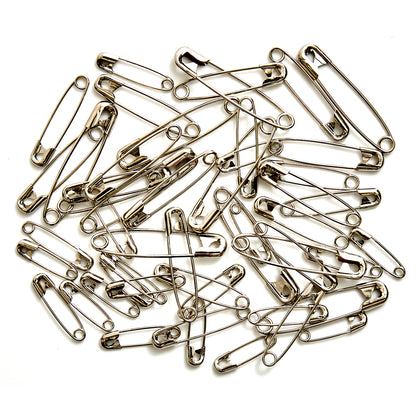 Glass jar of assorted silver safety pins