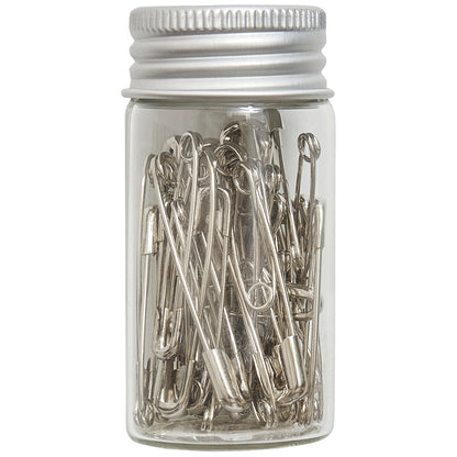 Glass jar of assorted silver safety pins