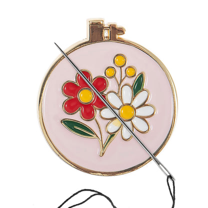 Round enamel magnetic needle minder with a colourful enamel embroidery hoop design with bright floral detailing