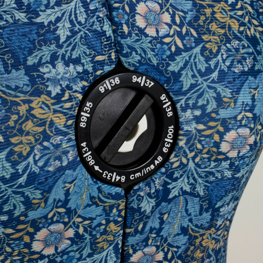 Adjustable dress form with floral fabric cover on a four-footed stand