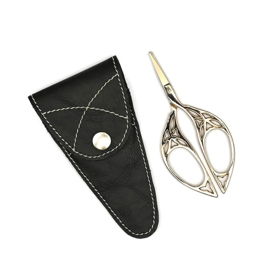 Small scissors with ornate handles beside a leather case