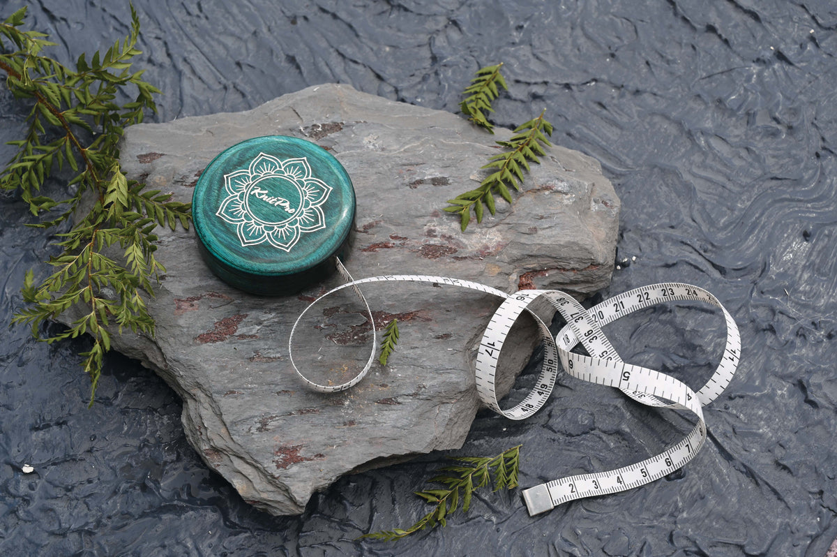 Round teal wooden retractable tape measure with a lotus design