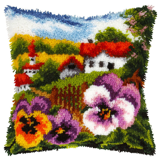 Finished Orchidea latch hook cushion showing a countryside landscape framed by pansies