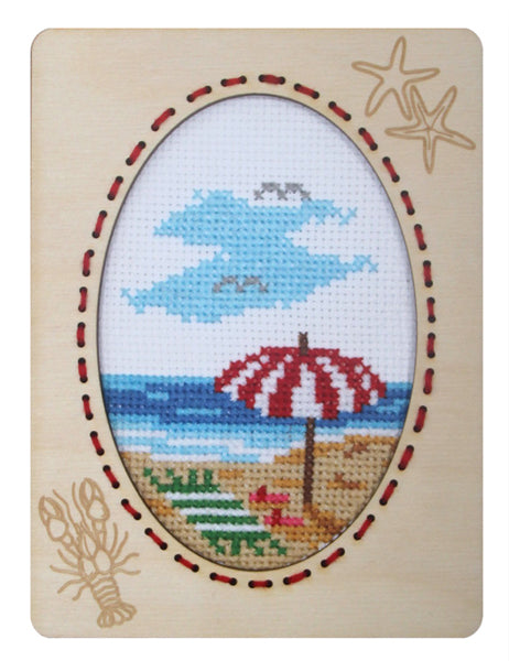 Orchidea cross stitch kit with a beach scene design in an engraved wooden frame