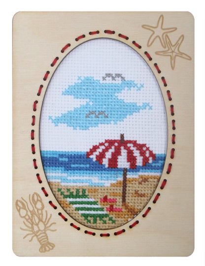 Orchidea cross stitch kit with a beach scene design in an engraved wooden frame