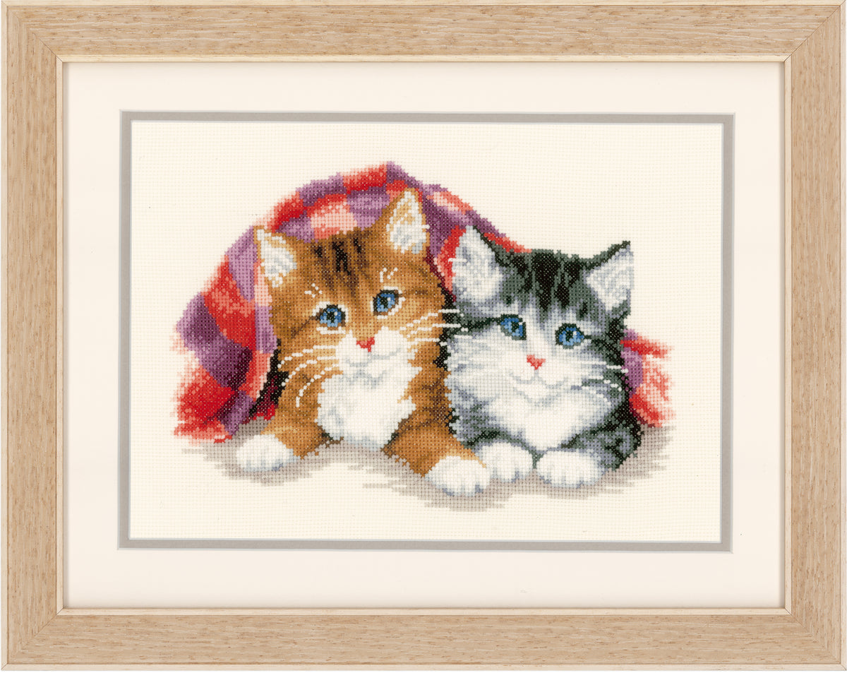 Cross stitch picture of a kitten peeping from under a rug