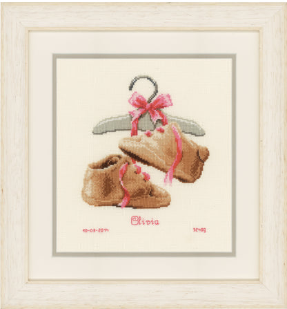 Counted cross stitch kit showing a pair of baby's first shoes