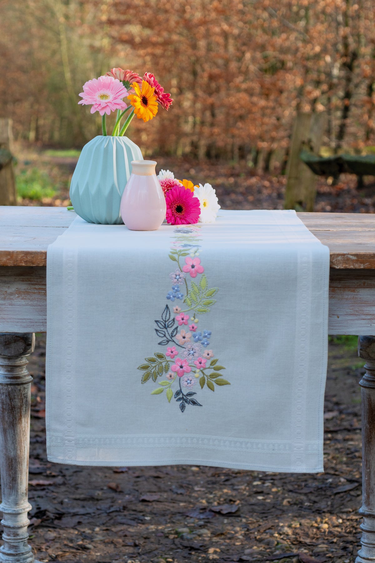 Light grey table runner embroidered with flowers and leaves