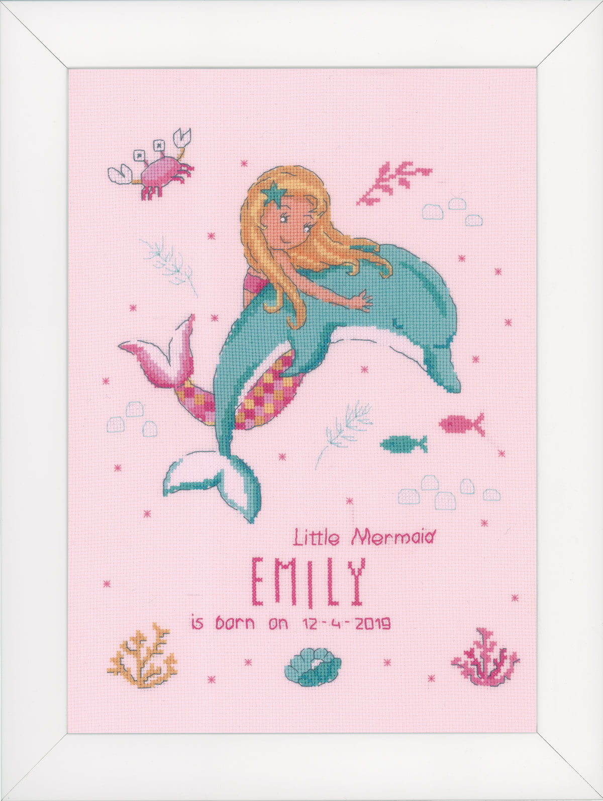 Cross stitch of a little mermaid and dolphin on pink fabric