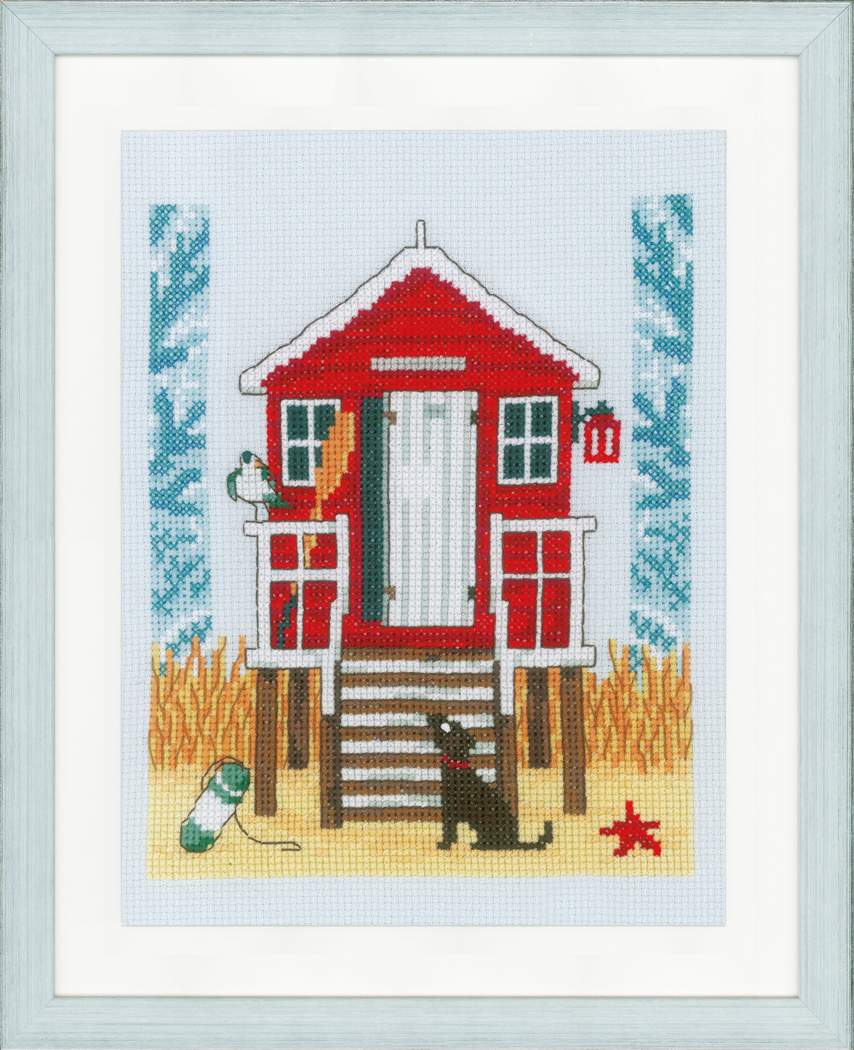 Cross stitch of a beach cabin on blue fabric