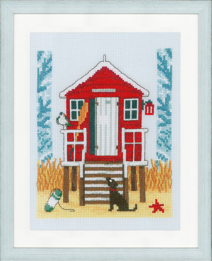 Cross stitch of a beach cabin on blue fabric