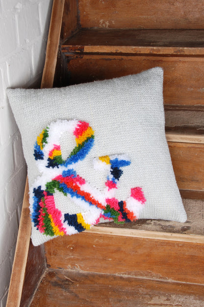 Latch hook cushion with a bright ampersand design