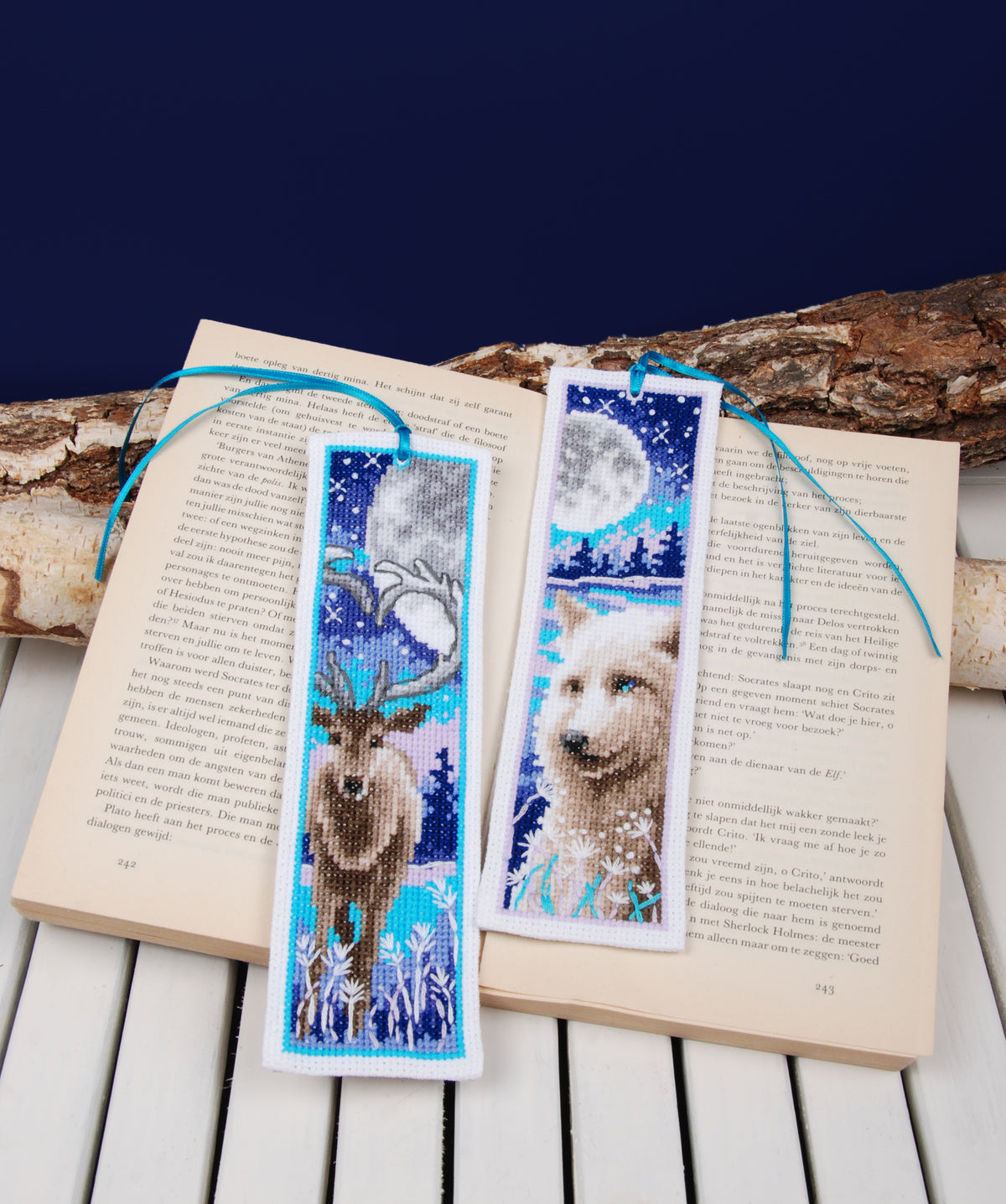 Two cross stitched bookmarks with a wolf and deer with moon design