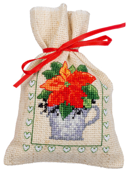 Three cross stitched Christmas gift bags tied with ribbon
