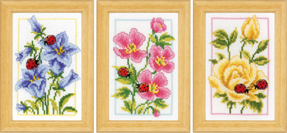 Three small cross stitched designs of flowers and ladybirds