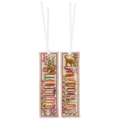Two cross stitched bookmarks with cats sitting on stacks of books