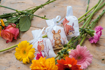 Three cross stitched woodland gift bags tied with ribbon