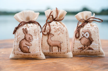Three natural linen gift bags cross stitched with winter animals