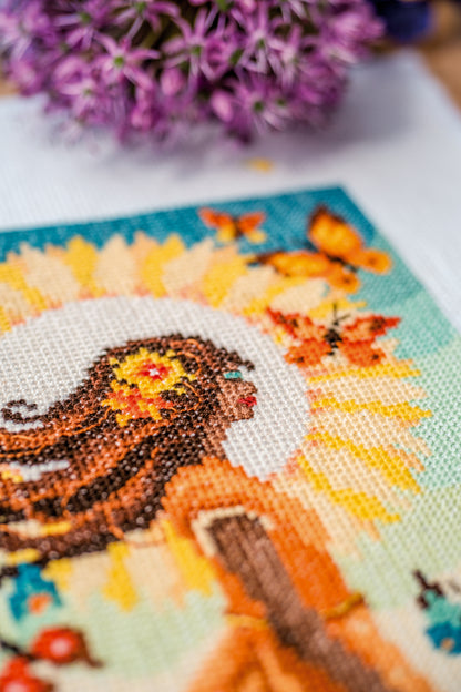 Cross stitch picture of a girl with the sun