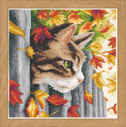 Cross stitch picture of a kitten by a garden fence