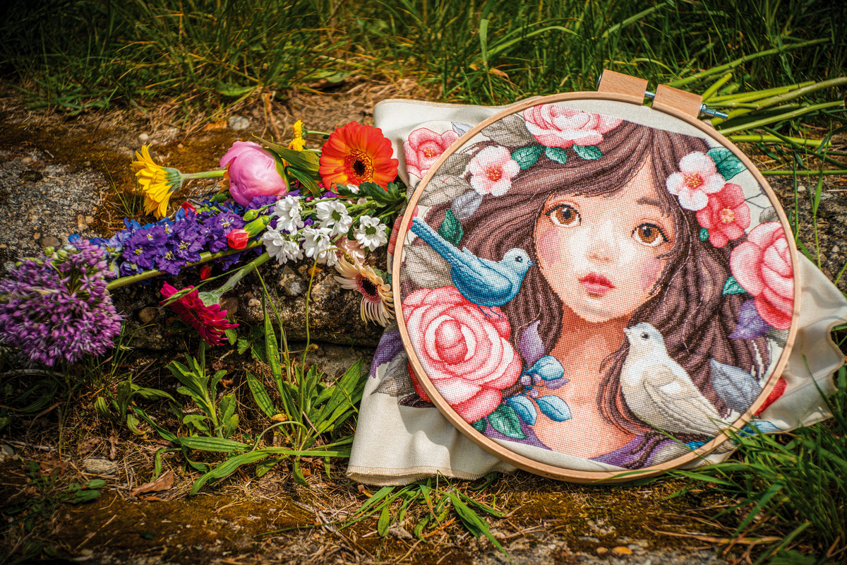 Cross stitch picture of a woman surrounded by roses