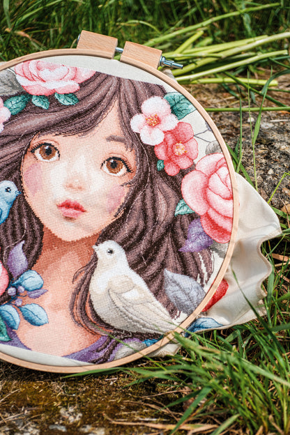 Cross stitch picture of a woman surrounded by roses