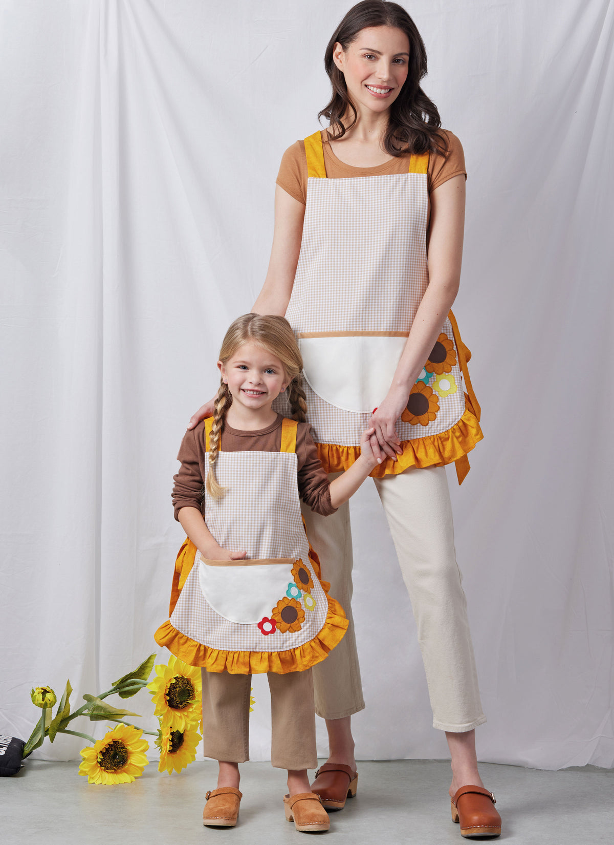 Simplicity S3119 pattern envelope showing aprons with contrast straps and floral appliques