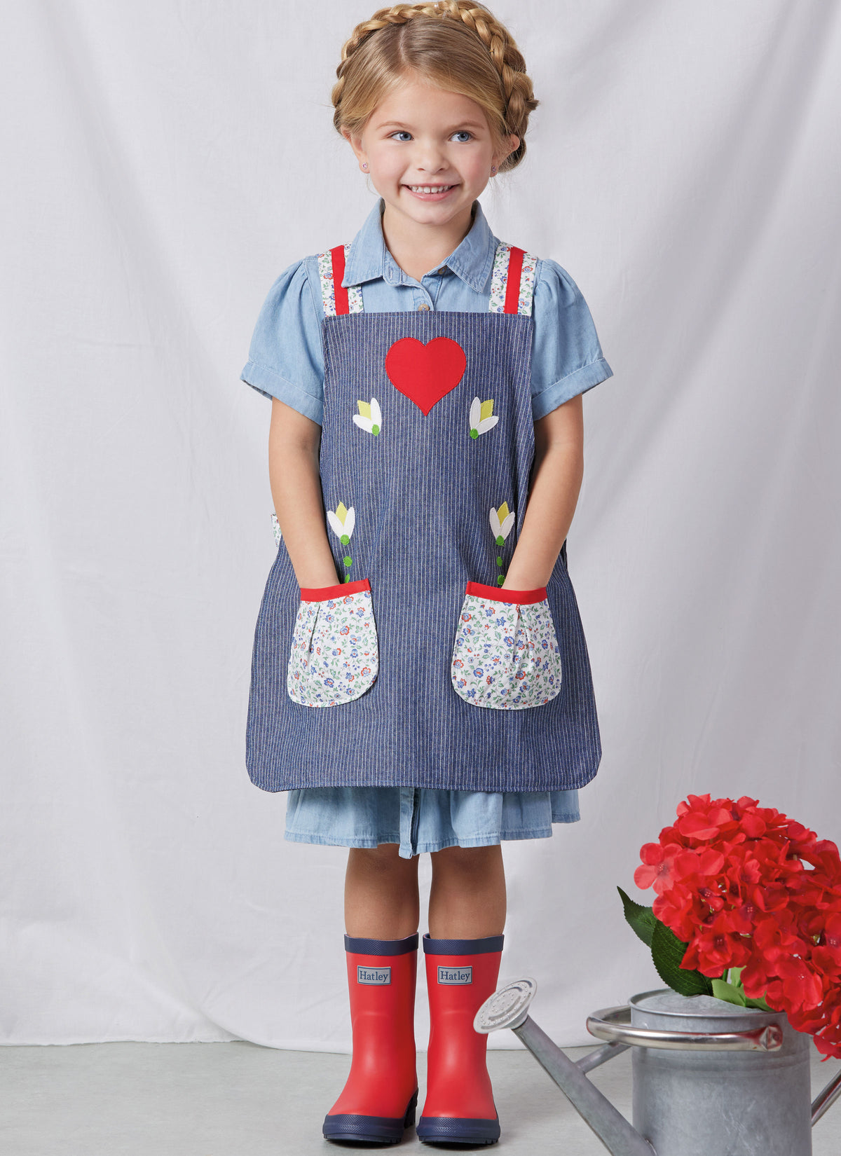 Simplicity S3119 pattern envelope showing aprons with contrast straps and floral appliques